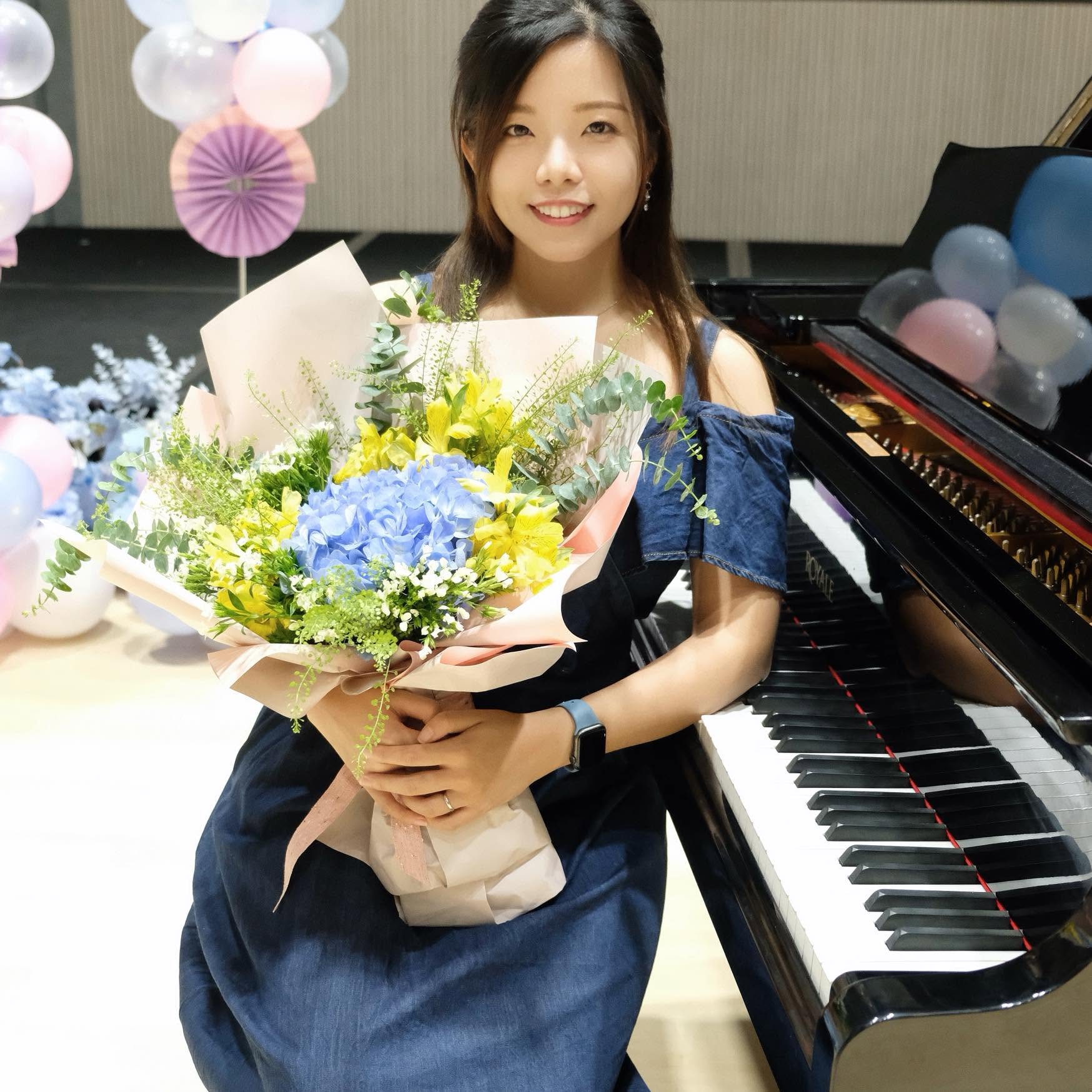 Miss Karen 老師手持花束，與三角鋼琴合影